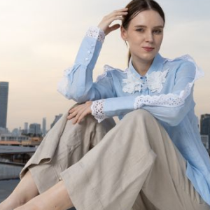 POYA sky blue lace-trimmed blouse and tan linen trousers, rooftop