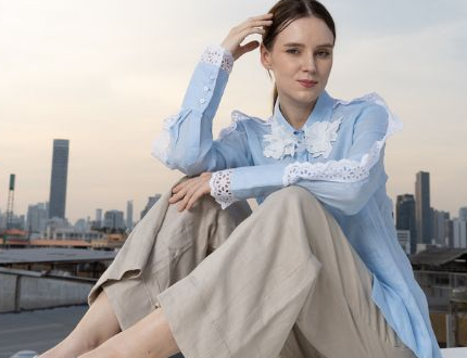 POYA sky blue lace-trimmed blouse and tan linen trousers, rooftop